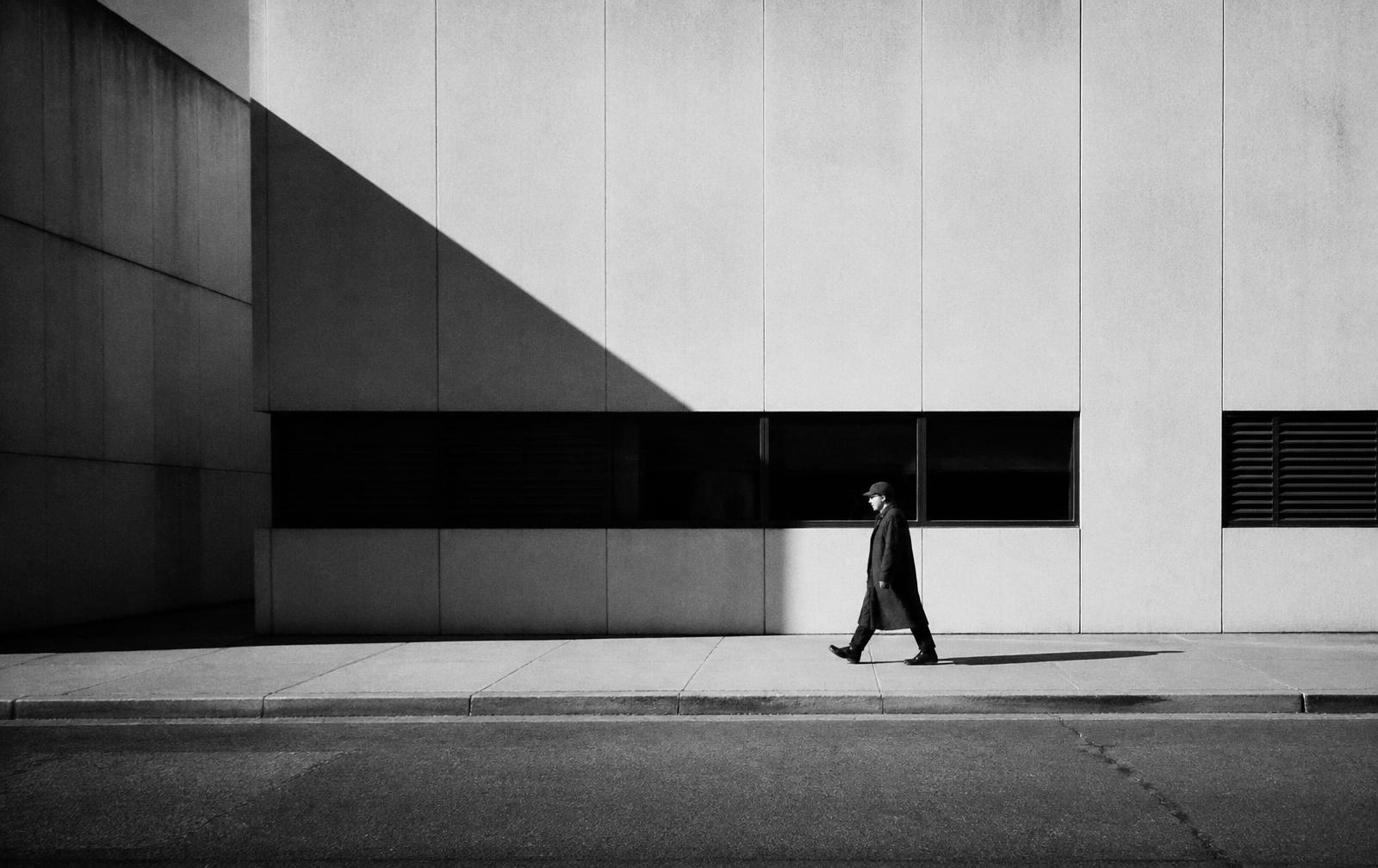 Lone figure walking past a modernist facade
